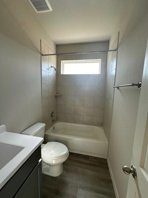 full bathroom featuring hardwood / wood-style floors, tiled shower / bath combo, toilet, and vanity