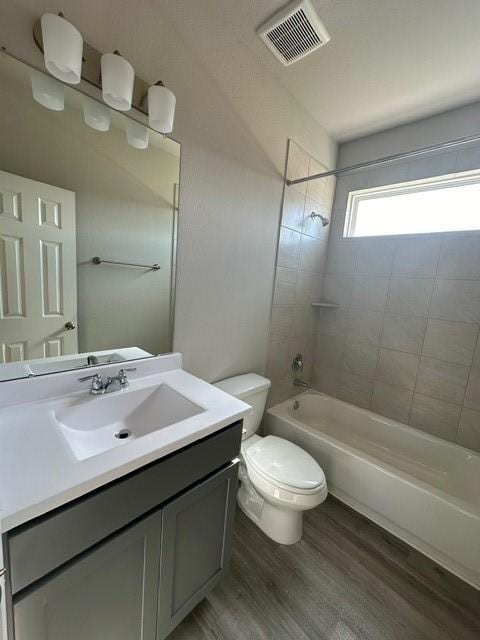 full bathroom with vanity, wood-type flooring, tiled shower / bath combo, and toilet