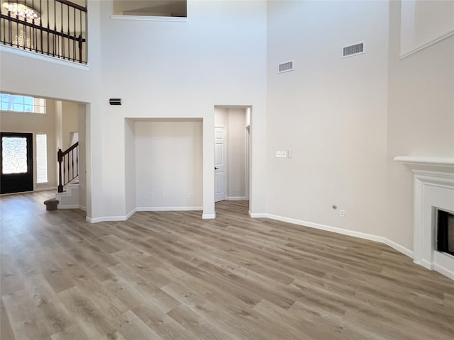 unfurnished living room featuring a towering ceiling and hardwood / wood-style flooring