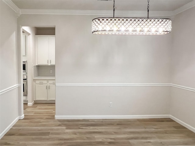 unfurnished dining area featuring light hardwood / wood-style floors and crown molding