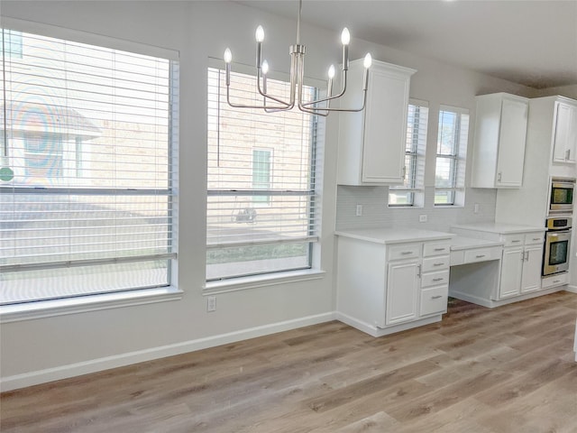 kitchen featuring stainless steel appliances, light hardwood / wood-style flooring, decorative light fixtures, decorative backsplash, and white cabinets