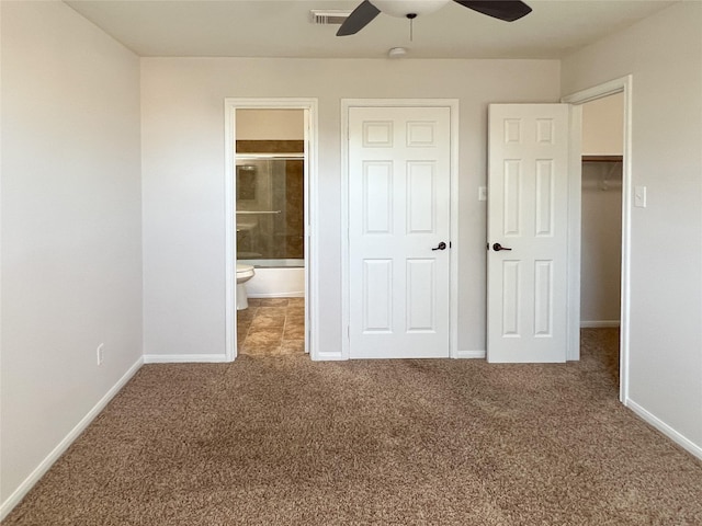 unfurnished bedroom featuring ensuite bathroom, a walk in closet, ceiling fan, carpet floors, and a closet