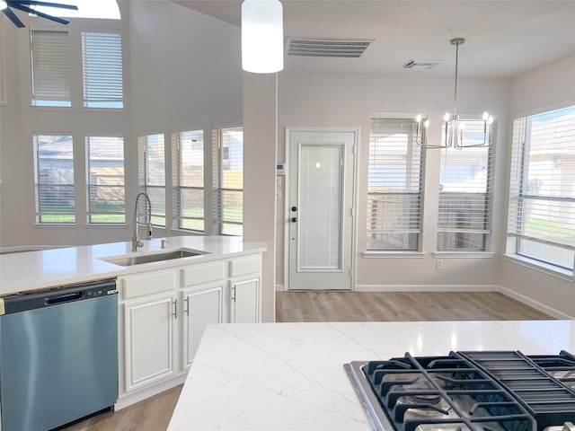 kitchen featuring white cabinets, sink, hanging light fixtures, stainless steel dishwasher, and a wealth of natural light