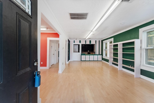 unfurnished living room featuring hardwood / wood-style floors, crown molding, and a textured ceiling