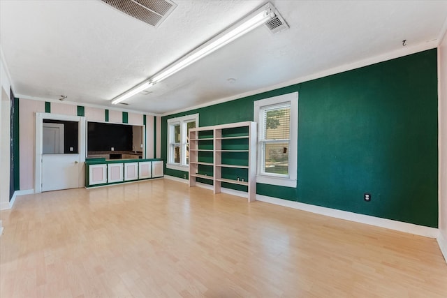 unfurnished living room featuring crown molding, a textured ceiling, and hardwood / wood-style flooring