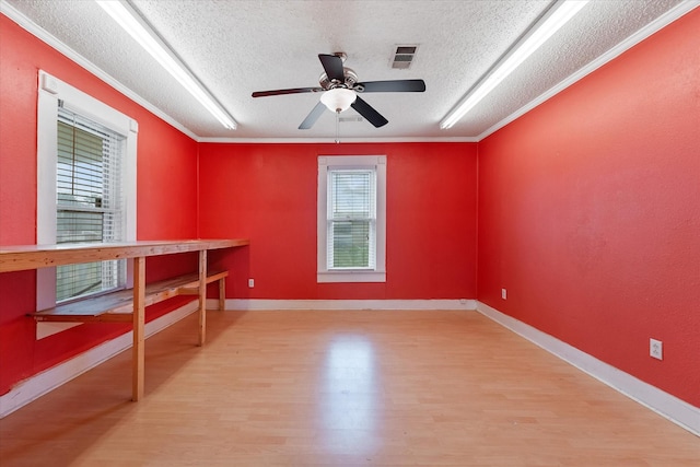 empty room with ceiling fan, light hardwood / wood-style flooring, a textured ceiling, and ornamental molding