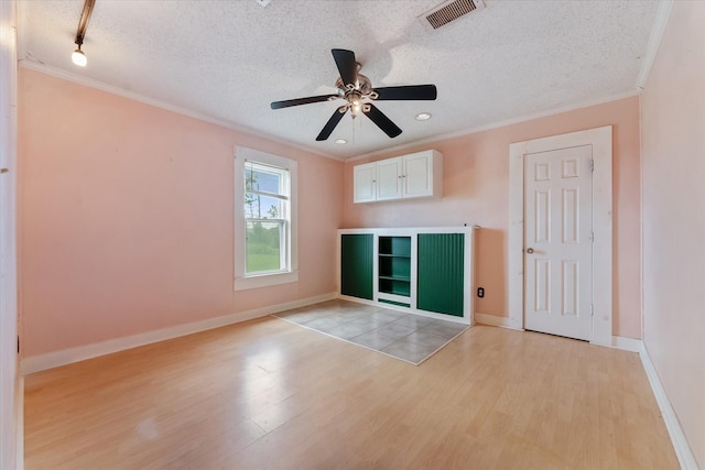 spare room with a textured ceiling, ceiling fan, light hardwood / wood-style floors, and crown molding