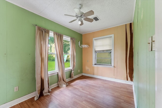 spare room with ceiling fan, wood walls, and light hardwood / wood-style floors