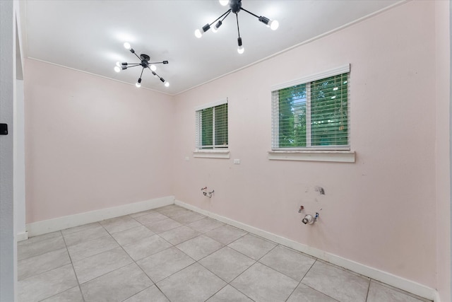 spare room with ornamental molding, light tile patterned floors, and a notable chandelier