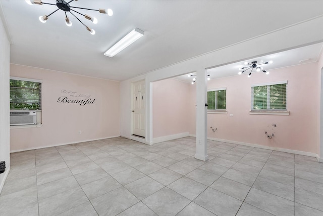 tiled empty room with cooling unit, a wealth of natural light, and a chandelier