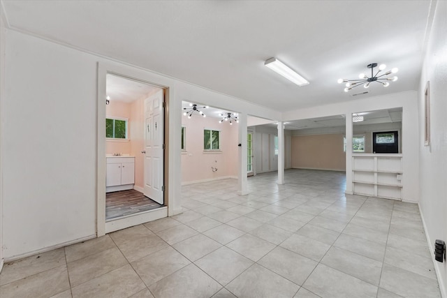 empty room with light tile patterned floors and an inviting chandelier