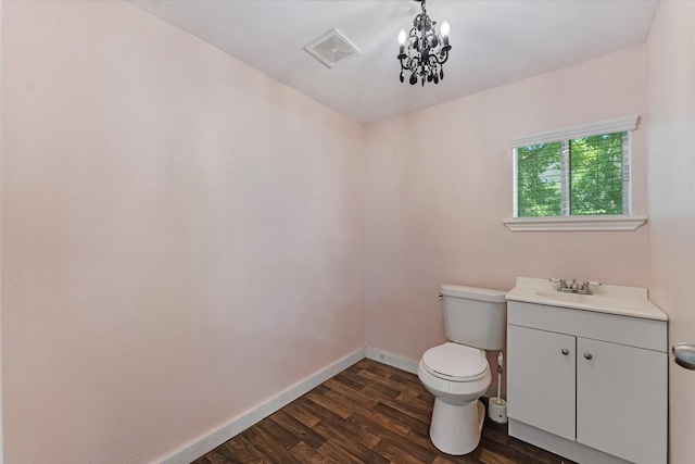 bathroom featuring hardwood / wood-style floors, a notable chandelier, toilet, and vanity