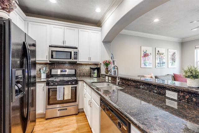 kitchen with white cabinets, appliances with stainless steel finishes, dark stone counters, and sink