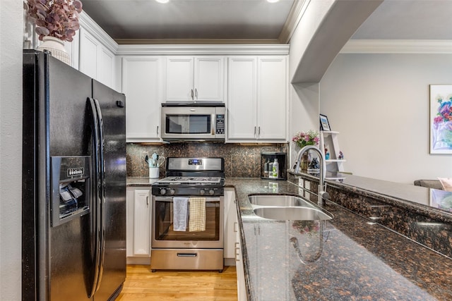 kitchen featuring sink, decorative backsplash, dark stone countertops, appliances with stainless steel finishes, and white cabinetry