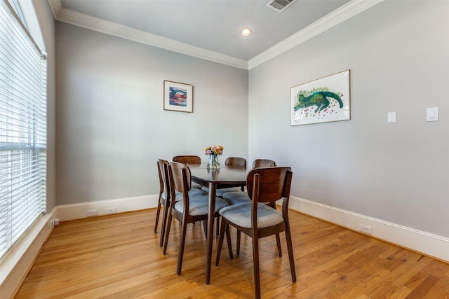 dining room with light hardwood / wood-style floors and crown molding