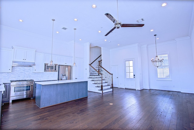 kitchen with pendant lighting, a center island, white cabinets, ceiling fan with notable chandelier, and appliances with stainless steel finishes