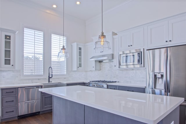 kitchen with decorative backsplash, appliances with stainless steel finishes, sink, pendant lighting, and a center island