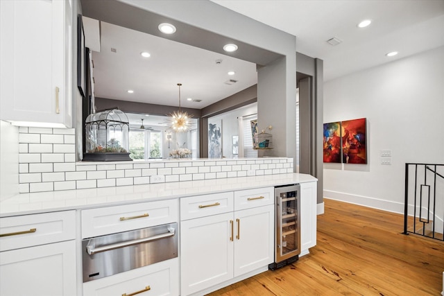 kitchen featuring decorative backsplash, white cabinetry, wine cooler, and light hardwood / wood-style flooring