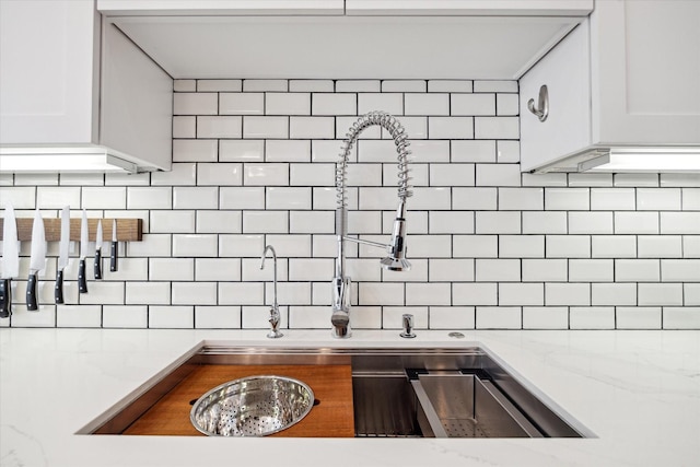 kitchen featuring decorative backsplash, white cabinets, and light stone counters