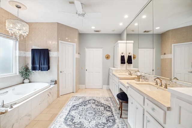 bathroom featuring tile patterned flooring, ceiling fan with notable chandelier, a relaxing tiled tub, and vanity