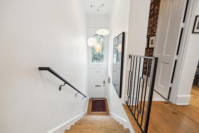 stairs with hardwood / wood-style flooring, a high ceiling, and an inviting chandelier