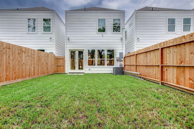 rear view of house featuring central AC and a lawn