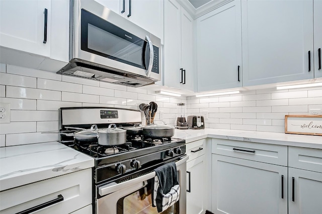 kitchen with decorative backsplash, light stone counters, white cabinetry, and stainless steel appliances