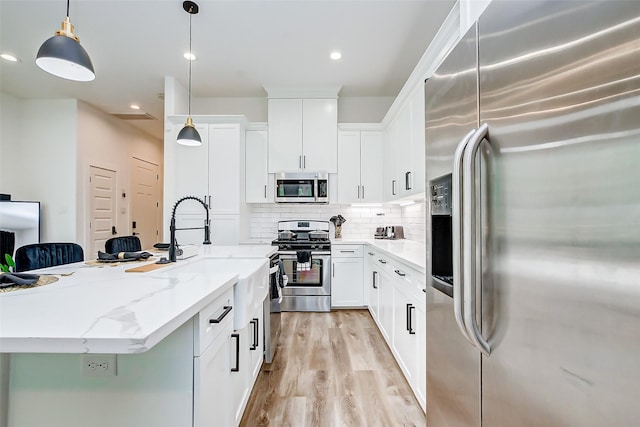 kitchen with light stone countertops, backsplash, stainless steel appliances, decorative light fixtures, and white cabinets