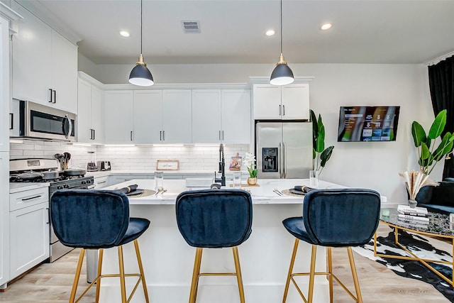 kitchen featuring an island with sink, white cabinets, and stainless steel appliances