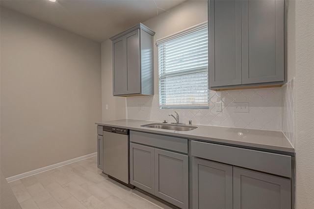 kitchen with stainless steel dishwasher, gray cabinets, sink, and tasteful backsplash