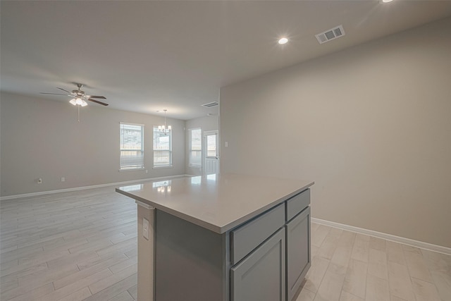 kitchen with gray cabinetry, a center island, light hardwood / wood-style flooring, decorative light fixtures, and ceiling fan with notable chandelier