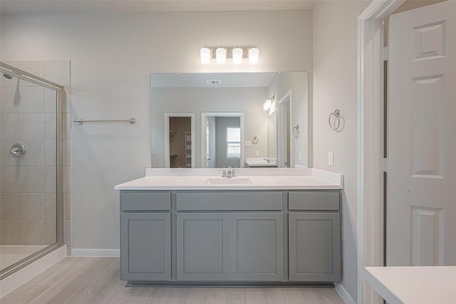 bathroom featuring hardwood / wood-style flooring, vanity, and walk in shower