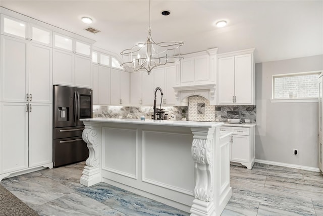 kitchen with stainless steel fridge, a center island with sink, and white cabinetry