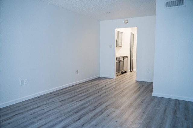 unfurnished room with light hardwood / wood-style flooring and a textured ceiling