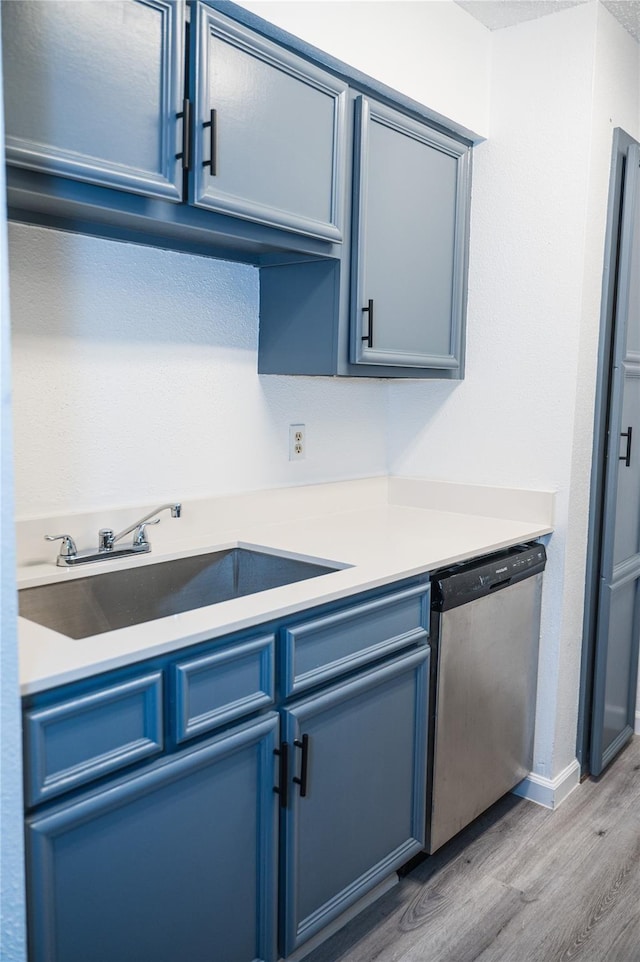 kitchen featuring blue cabinetry, sink, stainless steel dishwasher, and light wood-type flooring