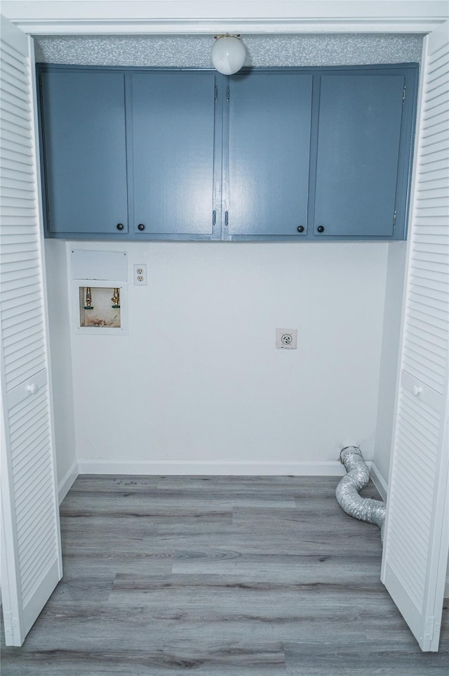 clothes washing area with electric dryer hookup, wood-type flooring, cabinets, and washer hookup