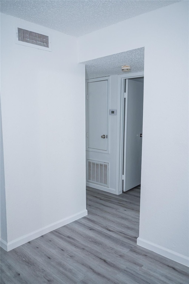 empty room with light hardwood / wood-style floors and a textured ceiling