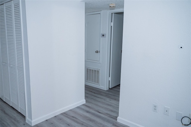 hallway featuring a textured ceiling and light hardwood / wood-style floors