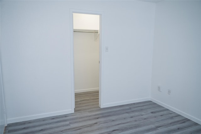 unfurnished bedroom featuring a spacious closet, light wood-type flooring, and a closet