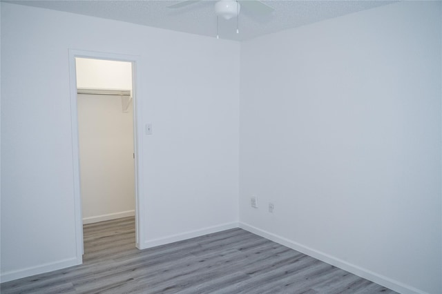 empty room featuring ceiling fan, light wood-type flooring, and a textured ceiling