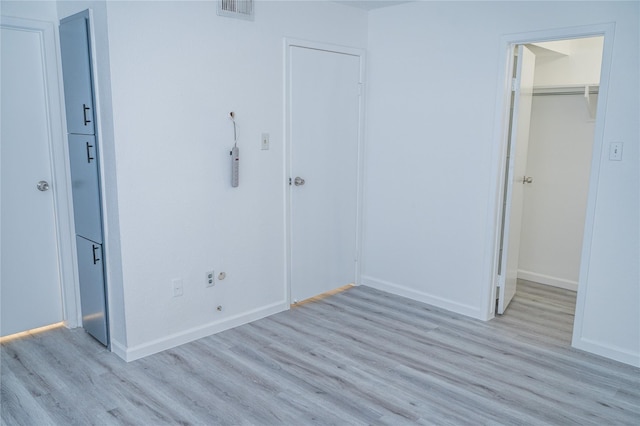 unfurnished bedroom with a spacious closet, a closet, and light wood-type flooring