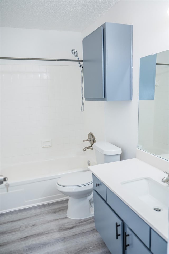 full bathroom with bathing tub / shower combination, wood-type flooring, a textured ceiling, toilet, and vanity