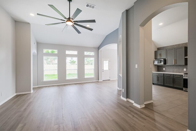 unfurnished living room with ceiling fan, light hardwood / wood-style floors, and vaulted ceiling