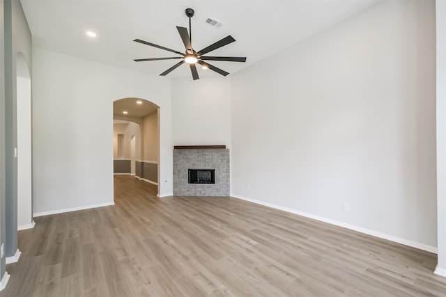 unfurnished living room with a tile fireplace, ceiling fan, and light hardwood / wood-style floors