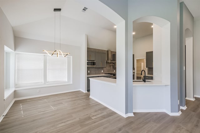 kitchen with sink, light hardwood / wood-style floors, decorative light fixtures, and appliances with stainless steel finishes