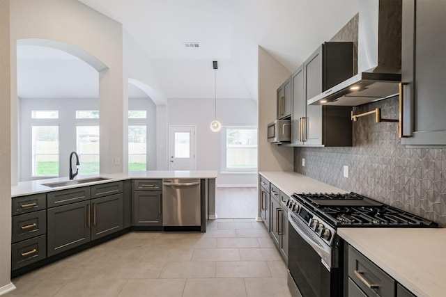 kitchen featuring appliances with stainless steel finishes, tasteful backsplash, sink, wall chimney range hood, and pendant lighting