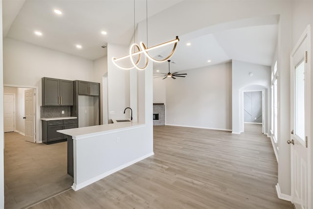 kitchen with ceiling fan with notable chandelier, sink, decorative light fixtures, high vaulted ceiling, and gray cabinets