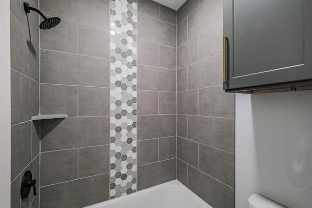 bathroom with tiled shower / bath combo and toilet