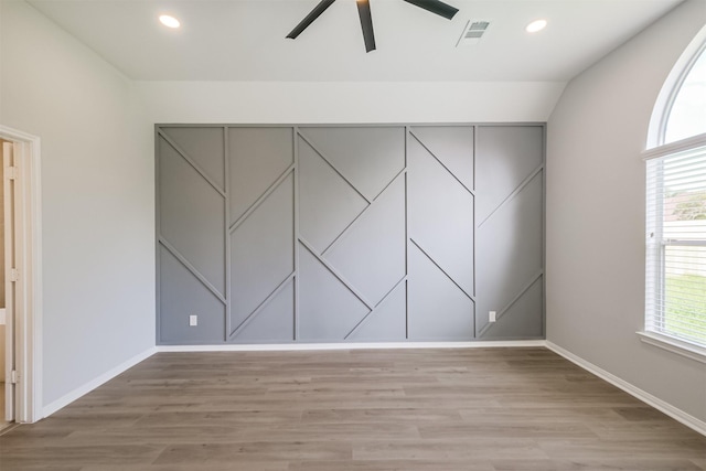 unfurnished room featuring light wood-type flooring, vaulted ceiling, a wealth of natural light, and ceiling fan