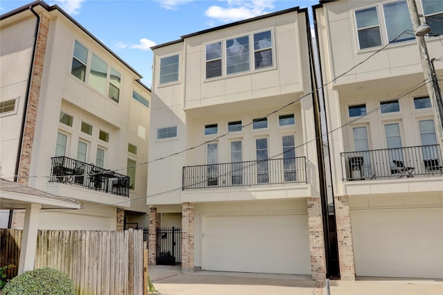 view of building exterior featuring an attached garage, driveway, and fence